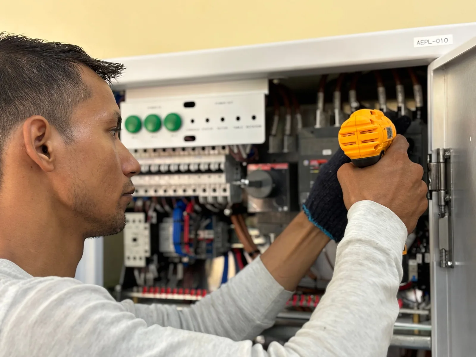 An electrician working on a commercial control panel, for panel upgrade in Oakville