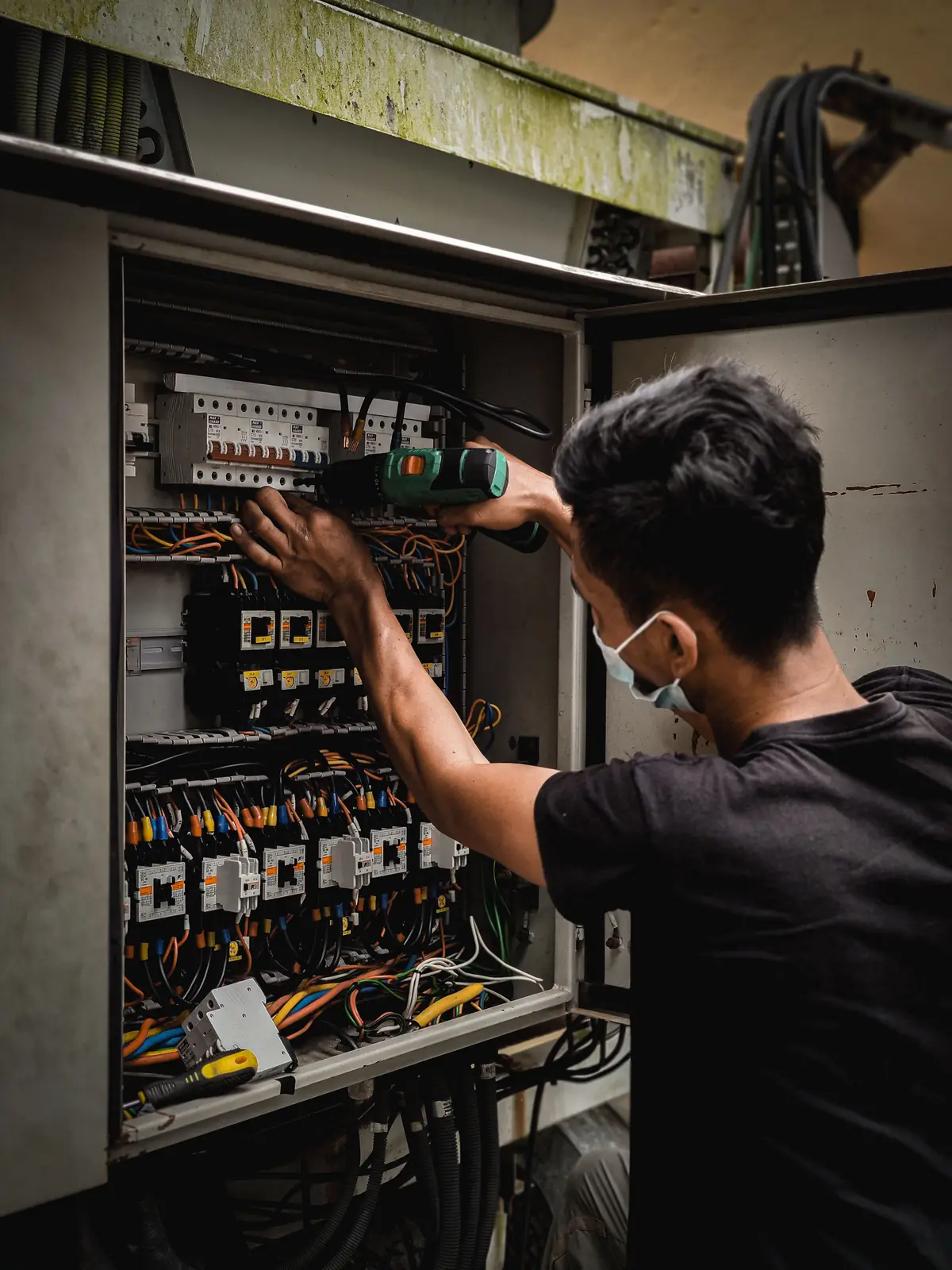 An electrician working inside a large distribution board, for commercial electrical in Oakville