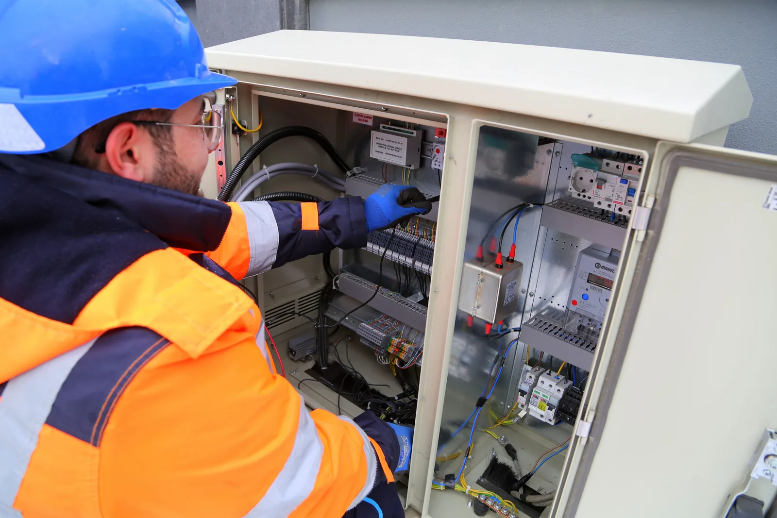 An electrician working in an outdoor service cabinet, for maintenance plans in Oakville